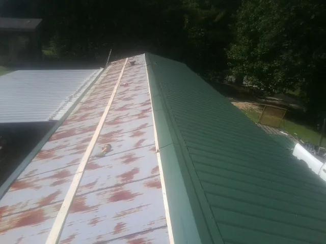 Old rusted panels beside newly installed green metal roofing — Wind Damage Roof Repair by Roofing Brothers in Gales Ferry