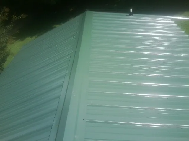 New green metal panels meeting at the ridge of a roof — Flat Roof Repair work by our crew in Gales Ferry