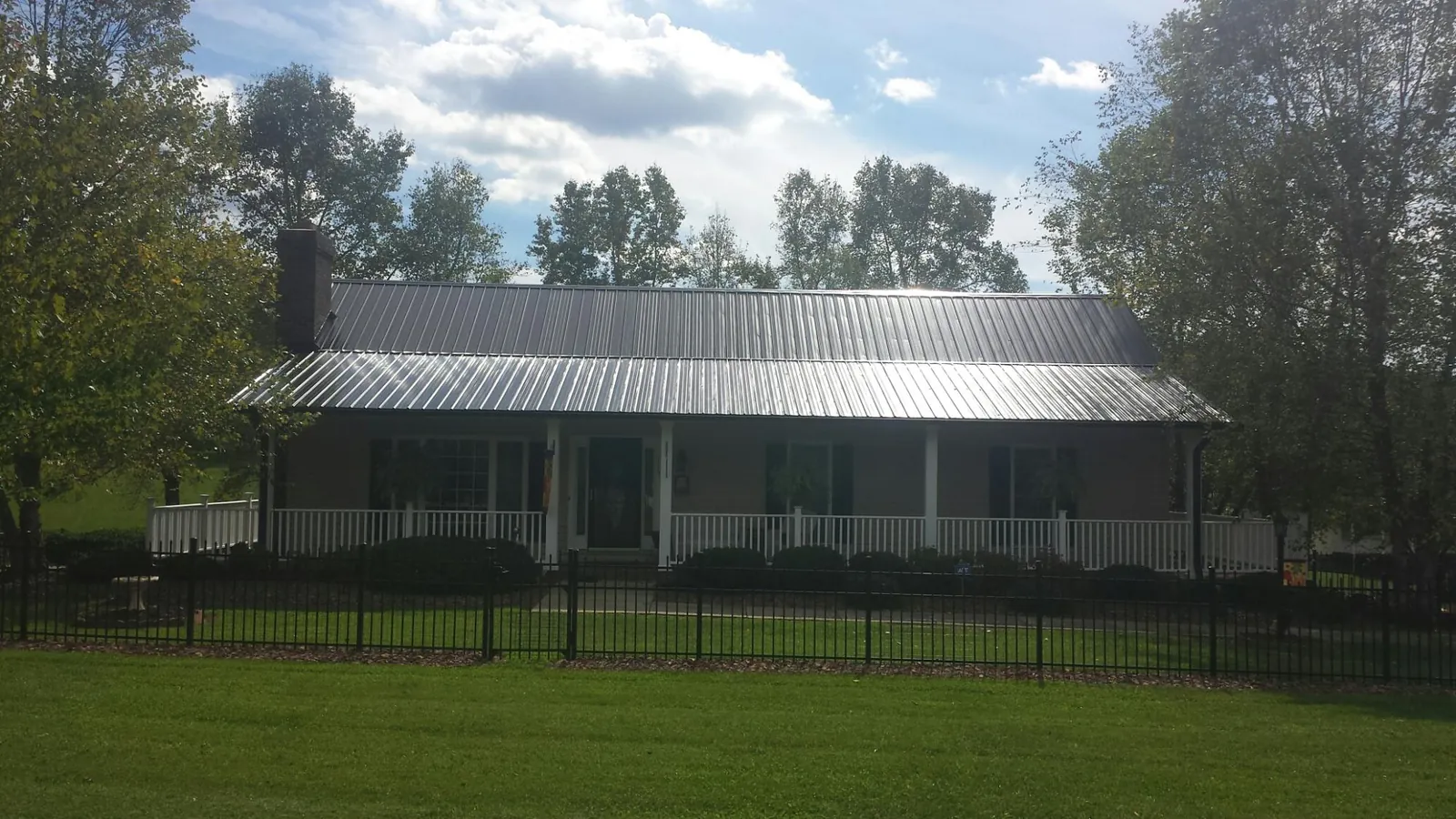Gray metal roof on a brick ranch with a full width front porch — Gutter Guard Installation work by our crew in Gales Ferry