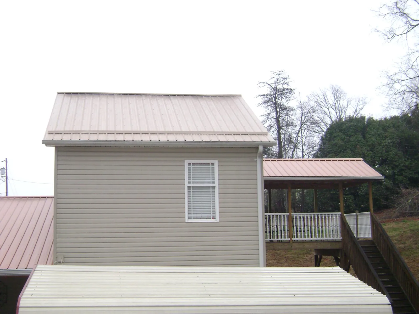 Tan metal roofs on a two story addition and attached porch, from a Roof Replacement job in Gales Ferry