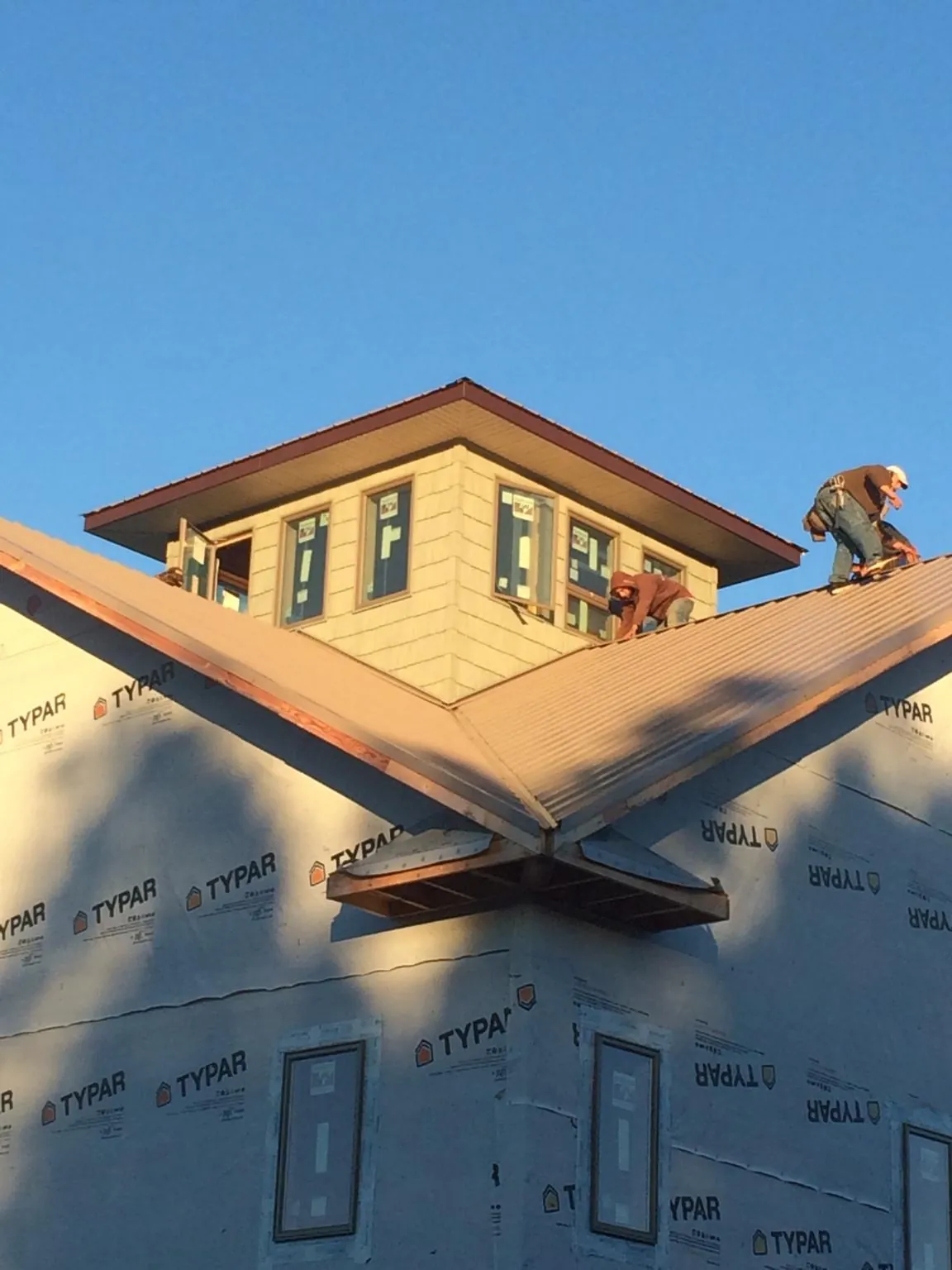 Roofers working around a rooftop cupola on a new metal roof at sunset — Roof Waterproofing in Gales Ferry by Roofing Brothers